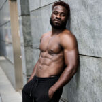 shirtless man leaning against a granite wall