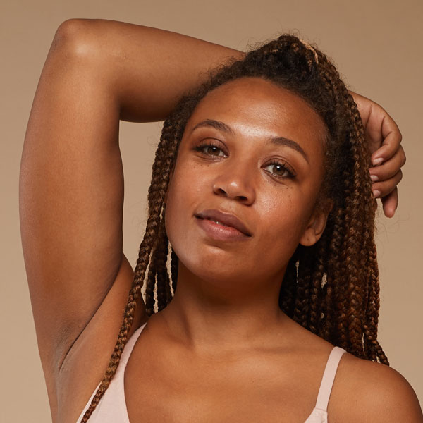 woman with long braids holding one arm up and resting it on her head