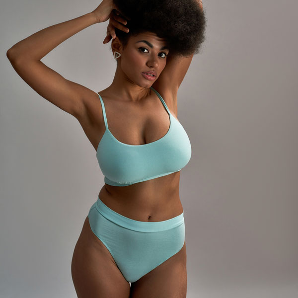 woman wearing blue with her arms up holding her hair