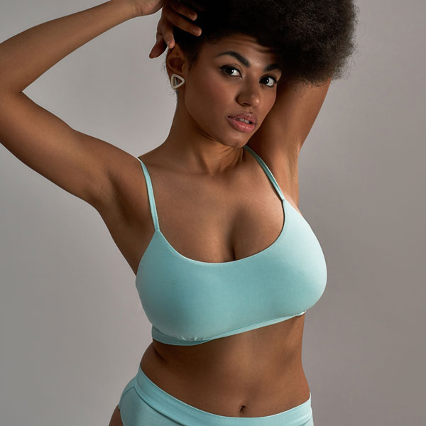 woman wearing blue with her arms up holding her hair