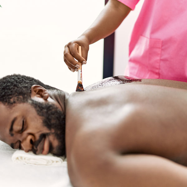 woman applying skincare mask to mans back