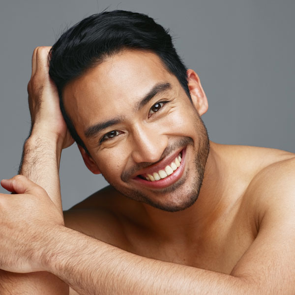 man with hand touching hair smiling at the camera