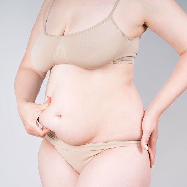 woman holding her stomach fat uncomfortably